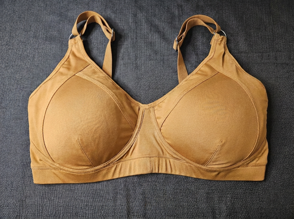 A tan molded-cup bra laid flat on a dark gray textured fabric background.
